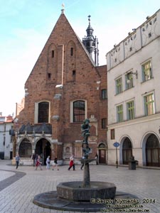 Фото Кракова. Старый Город. Фонтан с бронзовой скульптурой Жака (студента-бурсака) на Мариацкой площади (Plac Mariacki).
На втором плане - костёл Святой Варвары (Kościół św. Barbary).