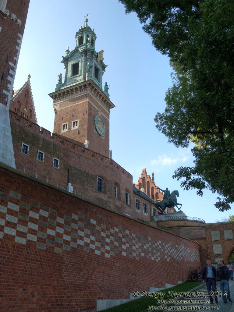 Фото Кракова. Вавель (Wawel). Стена с кирпичами с именами дарителей и Часовая башня (Wieża Zegarowa), вид со стороны подъезда к Гербовым воротам.