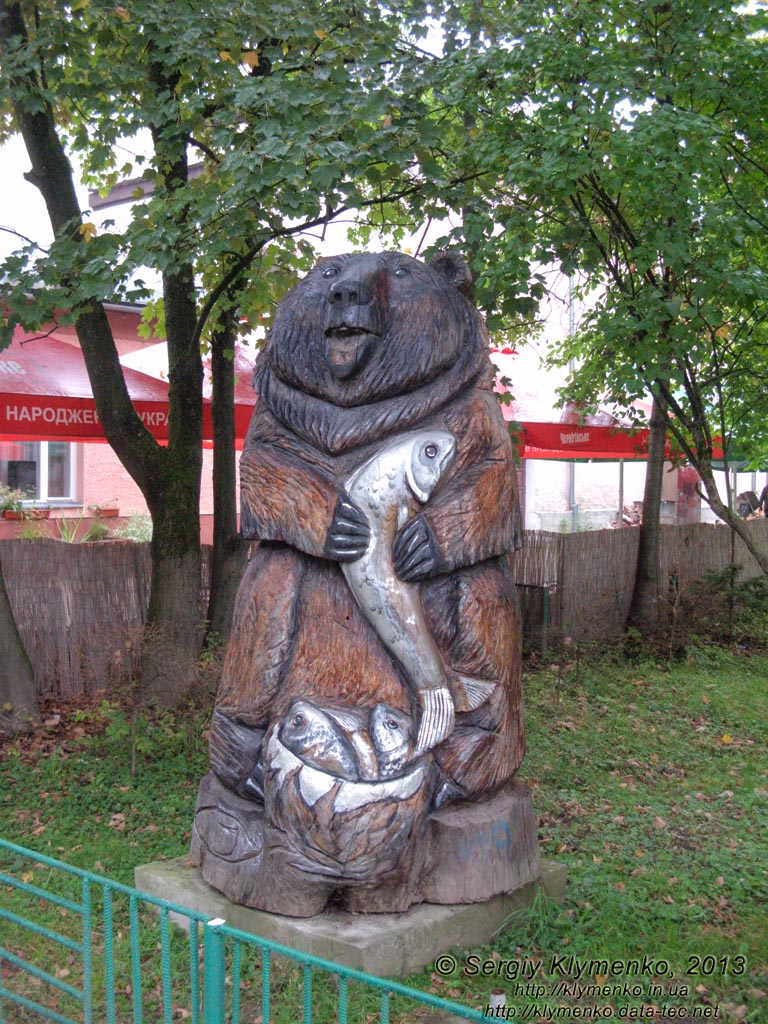 Закарпатская область, Свалява. Фото. На углу улиц Тараса Шевченко и Пушкина (перед кино-рестораном «Европа»). Вырезанная из дерева скульптура медведя с форелью.
